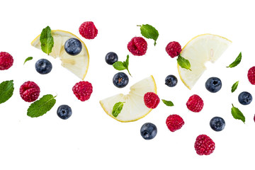 Creative layout, background, with fresh berries, simple pattern on white background. Raspberry, blueberry, mint leaves, slices of lemon.
