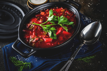 Ukrainian Russian traditional hot dish - borsch soup, with greens, garlic, rye bread, on a dark table