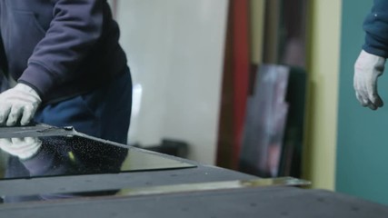 Cutting glass process. Men in gloves cutting glass. Close-up shot