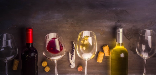 Bottles of red and white wine with wine glasses on table with copy space, toned image, banner