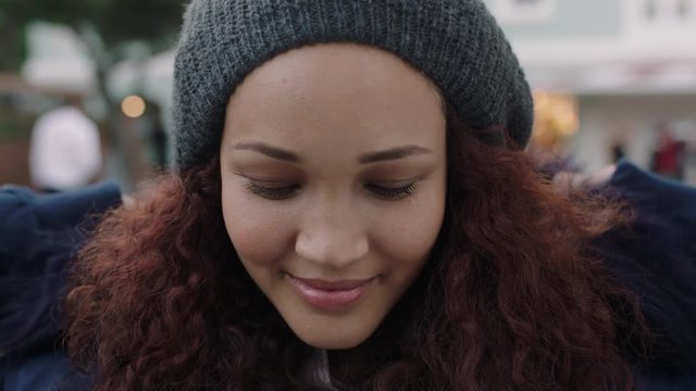 close up portrait of young beautiful mixed race woman with frizzy hair smiling enjoying wearing beanie fur coat looking at camera