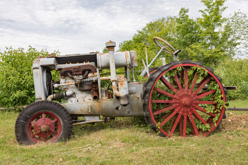Fototapeta na wymiar Antique tractors in field with dense undergrowth around them