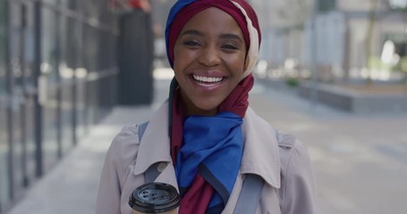 portrait young successful african american business woman laughing enjoying relaxed urban lifestyle beautiful black muslim female wearing traditional hijab headscarf in city holding coffee