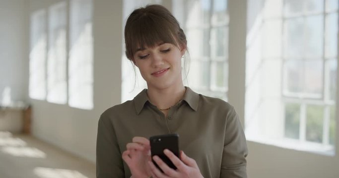 Portrait Of Beautiful Young Woman Using Smartphone Browsing Messages Texting Enjoying Social Media Online Communication On Mobile Phone Technology In Apartment Office Real People Series