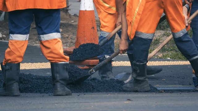 Road workers lay asphalt