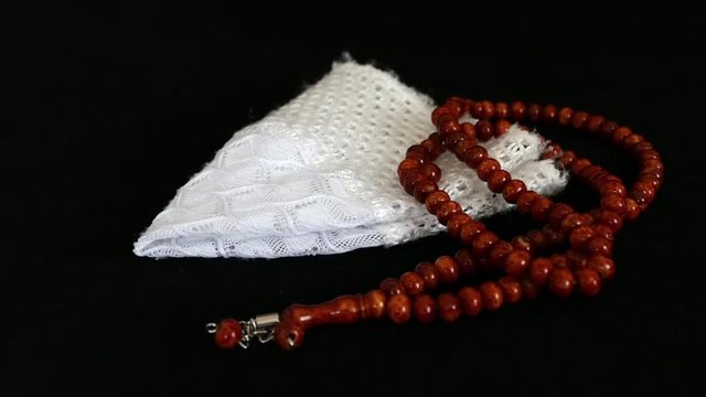 Uses a Muslim skullcap and prayer beads, Islamic symbols,
