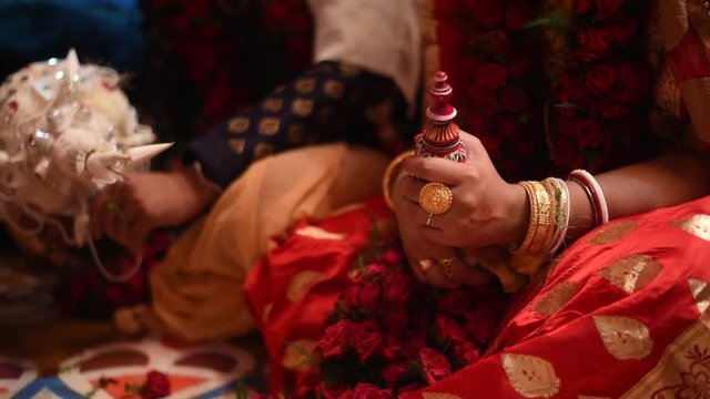 Closeup shot of hands of bride and groom in a colorful Bengali indian wedding. Blur to focus shift