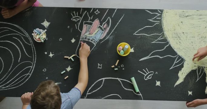 multi ethnic children drawing coloring space pictures together on blackboard using chalk happy kids enjoying fun creativity top view