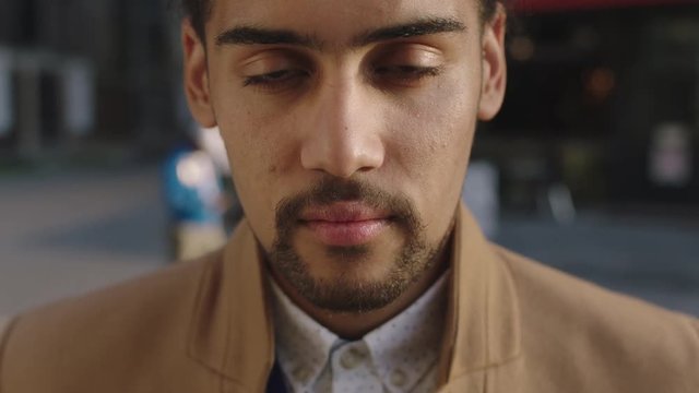 close up portrait of young mixed race businessman looking up slow motion confident pensive in city