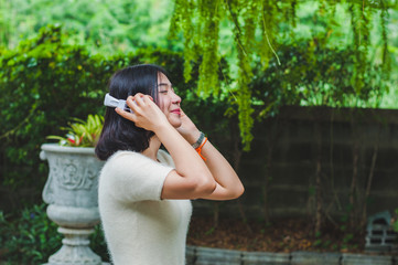 Naklejka premium Beautiful Asian girl listening to music in the garden.