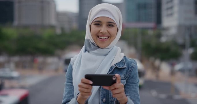 portrait young muslim woman student using smartphone in city enjoying texting browsing messages watching entertainment on mobile phone wearing hijab headscarf