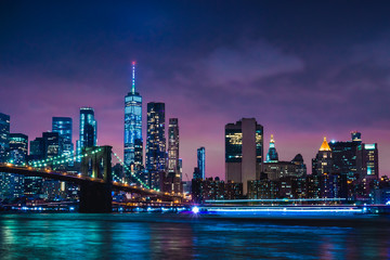 Skyline of downtown New York City Brooklyn Bridge and skyscrapers over East River illuminated with lights at dusk after sunset view from Brooklyn