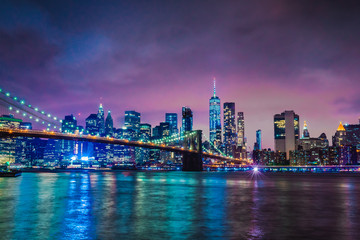Skyline of downtown New York City Brooklyn Bridge and skyscrapers over East River illuminated with...