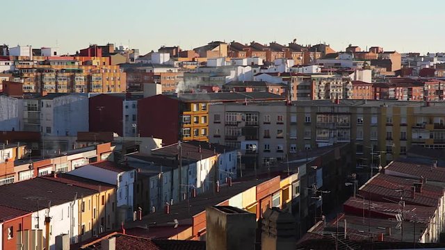 
Azoteas, tejados y edificios a distintos niveles de una ciudad, con chimeneas echando humo y antenas de television en los tejados