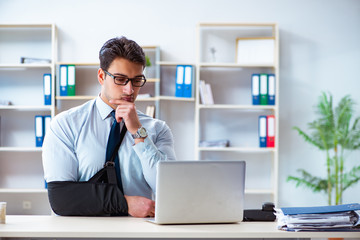 Businessman with broken arm working in office