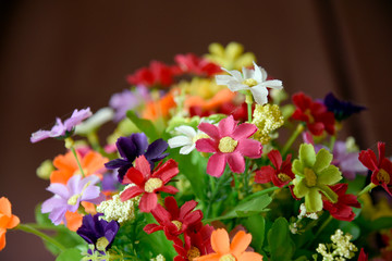 Many fake flowers are in the same bouquet. Color full of fabric flowers.