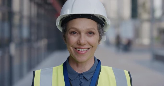 portrait successful senior construction engineer woman smiling enjoying professional career success wearing hard hat safety helmet slow motion reflective clothing
