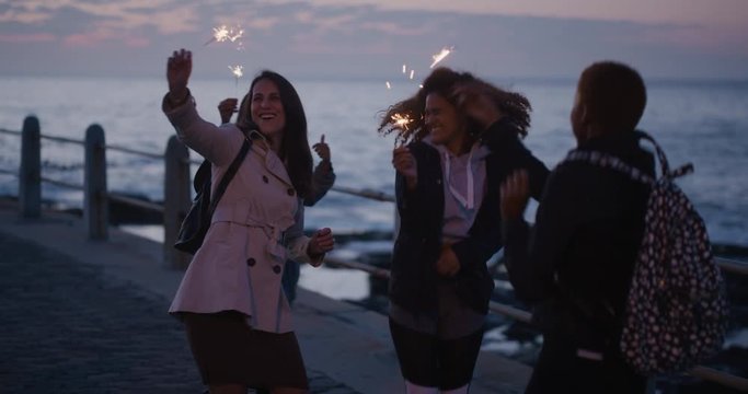 portrait diverse group of women friends waving sparklers dancing happy enjoying new years eve celebration multi ethnic girlfriends celebrating birthday on evening seaside sunset