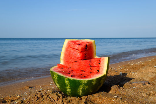 The cut watermelon lies on the seashore. Watermelon in the sea