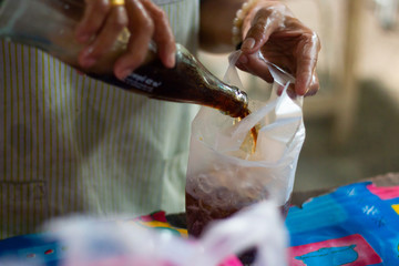 pouring coca cola or pepsi fresh sweet water in ice bag in market .