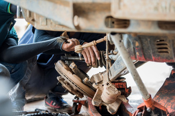Technician disassemble the driving shaft of the car in the garage