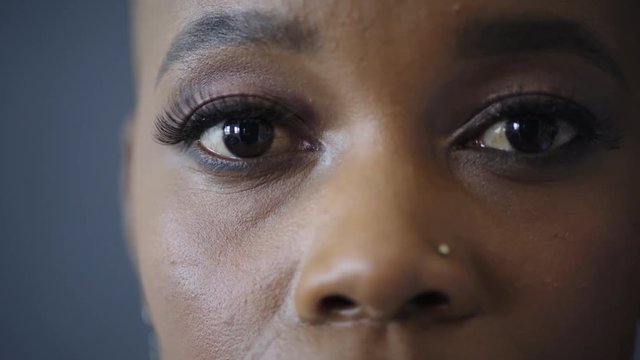 close up of beautiful african american woman eyes opening looking at camera wearing makeup nose piercing