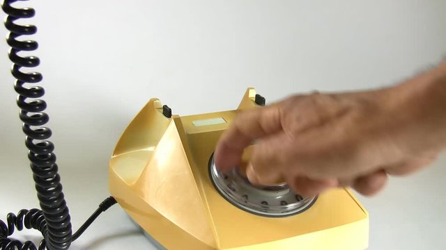 Man lifting old aged landline telephone receiver and dialing number; close up, audio, white with shadows background