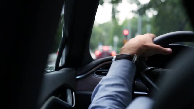 Smooth shot of a man driving wearing a blue shirt and a watch. Subtle slow motion makes this a fluid and an elegant shot.