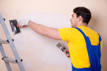 Young contractor employee applying plaster on wall