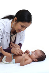 Cheerful female pediatrician holds newborn baby - 215450484