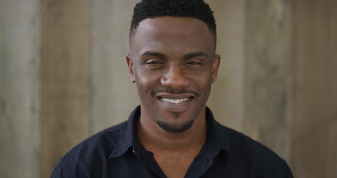 portrait of attractive young african american man smiling confident enjoying successful lifestyle wearing black shirt slow motion