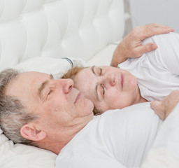 elderly couple sleeping together on the bed