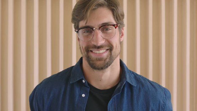 close up portrait of attractive young hipster man wearing glasses laughing happy looking confident at camera arms crossed handsome positive caucasian male 