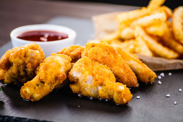 Chicken nuggets with french fries on black stone plate