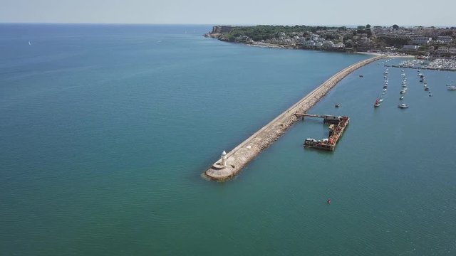 Aerial view of breakwater and harbour of Brixham, England. Boats are docked off shore.