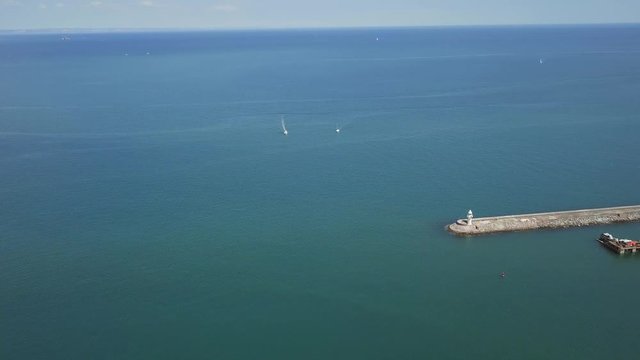 Aerial view of ocean off Brixham coast. Lighthouse in fish town in England.