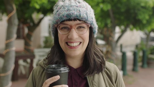 portrait of friendly hipster woman wearing funky glasses smiling cheerful at camera holding coffee beverage enjoying relaxed urban lifestyle