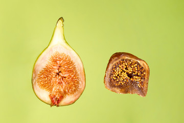 Sliced fresh fig and dried fig in front of green background
