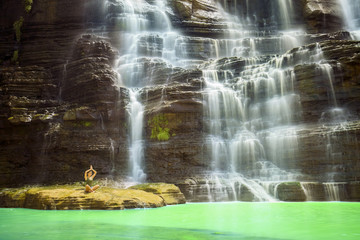 Asian woman meditates in the Cigangsa waterfall
