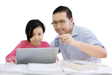 Father is helping his daughter to use a laptop