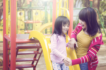 Mother and daughter having fun with slides outdoor