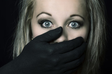 Frightened blonde woman grabbed by black hands on her face artistic conversion