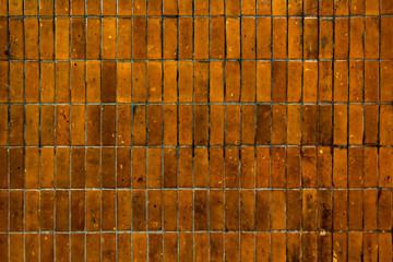 Old grungy yellow ceramic tile bricks wall in urban.