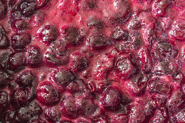 Cooking cherry jam.Cooked dark red cherries and red sugar syrup with foam.Interesting background. Site about fruits, berries,food,cuisine and cooking.