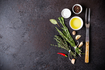 Olive oil, thyme and rosemary on black background