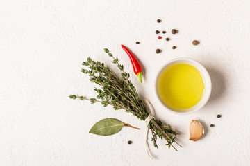 Olive oil and bouquet of thyme on a white stone background
