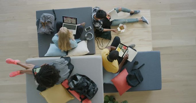 young group of multi ethnic college students study together using mobile technology working on project exam in modern recreational workspace top view
