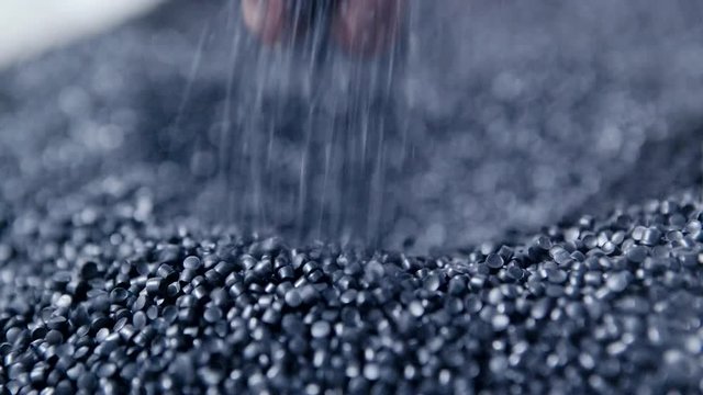 Hands lift white polymer granules from a cloth bag in a garbage recycling plant. Plastic pellets are crumbling or poured from the palms. Raw materials for recycled plastic are used in manufacturing.