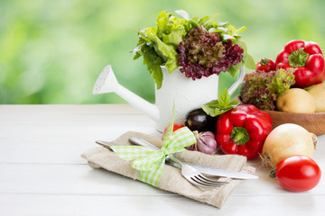 Fresh  raw vegetables in wooden plate  , fork and knife on white wooden table. Healthy eating and dieting concept