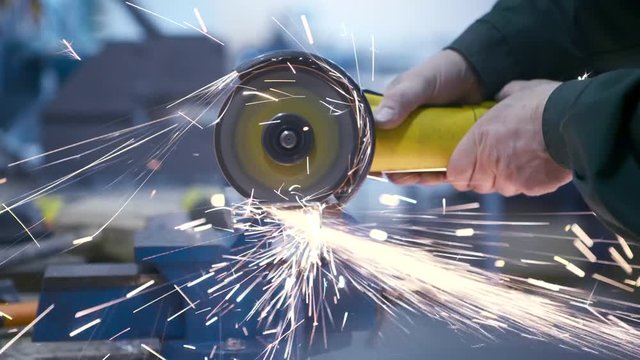 Closeup of how round piece is cut off from metal hollow pipe using cutting disc and an angle grinder. Artisan cuts piece from tin pipe using an angle grinder